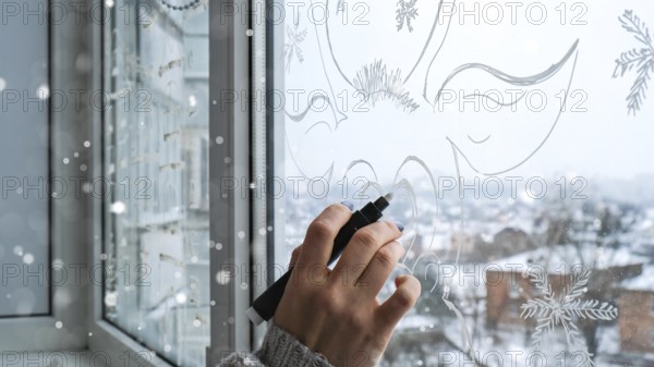 Female hand painting Christmas deer painted on window glass. Christmas winter decor on the window