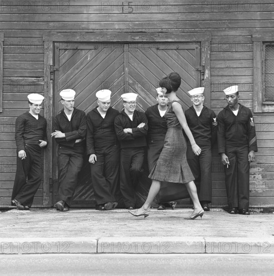 Fashion in the 1960s. A group of American sailors are standing at the docks on shore leave and