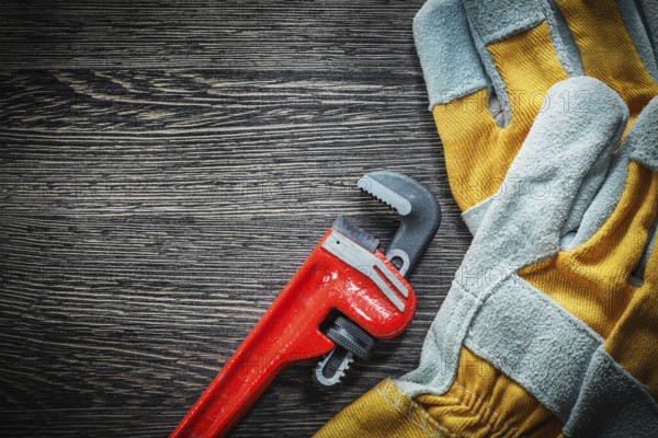 Plumbing adjustable wrench safety gloves on wooden board