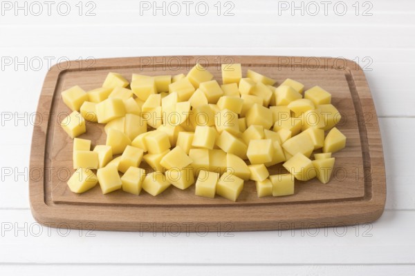 Food, Wooden board with fresh diced potatoes on a light gray background. Stage of cooking vegetable