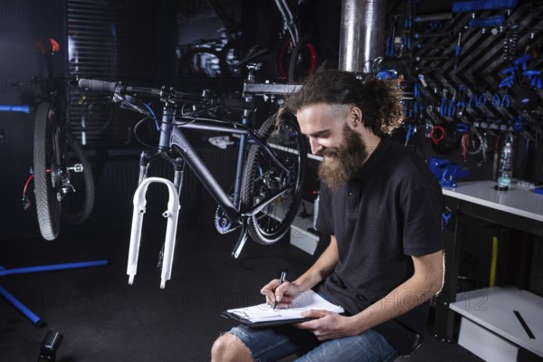 Bicycle Workshop Technician Doing Administrative Work. Bicycle mechanic writing in his checklist