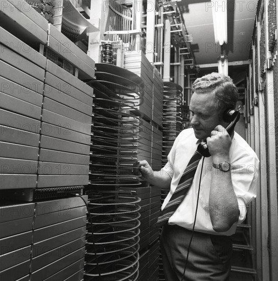 Telephony in the 1970s. A man in a room with an automatic switchboard connecting the calls through