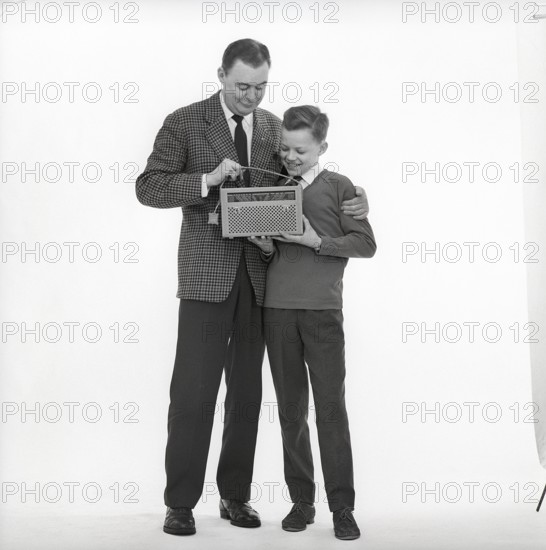 In the 1960s. Father and son with a radio. It's a typical 1960s radio with a cover of perforated