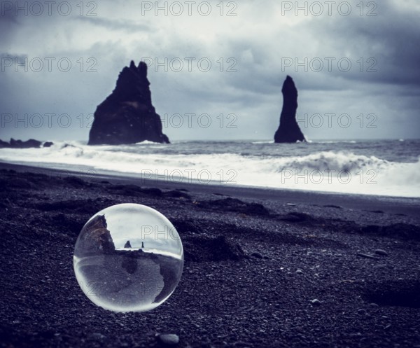 Cold sea water rolling on wet sand near rough stony cliffs on stormy day on Reynisfjara Black Beach