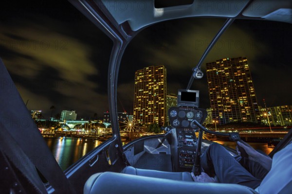 Helicopter cockpit flies in Honolulu skyline by night, Oahu, Hawaii, with pilot arm and control