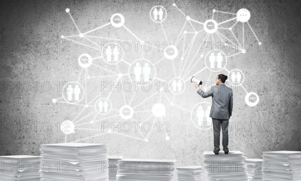 Businessman with speaker in hand standing on pile of documents with social network structure on