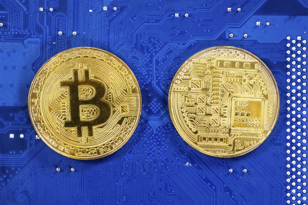 Virtual cryptocurrency money Bitcoin golden coins on a computer printed circuit board PCB. The