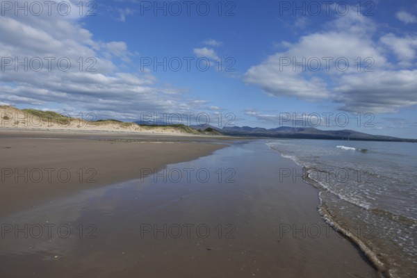 Beach and dunes with calm sea, in the background the mountains of Snowdonia National Park, Ynys