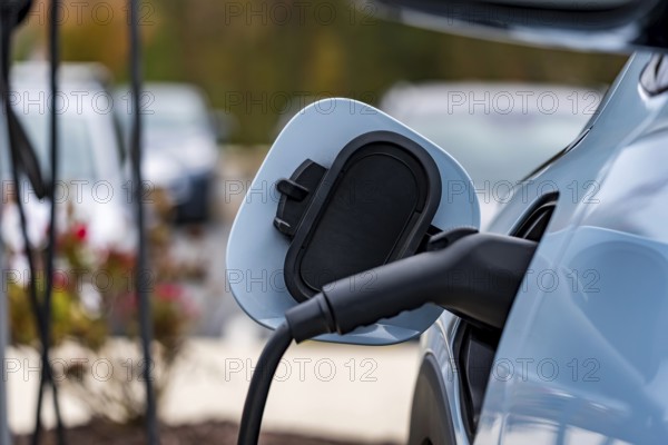 An electric vehicle recharges at a station while its owner is at work, allowing for a fully charged