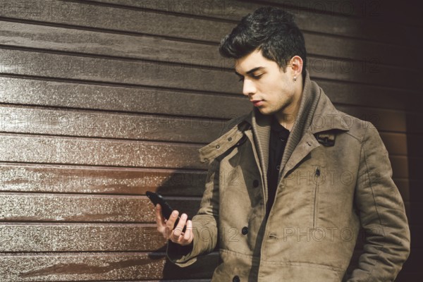 Portrait of young handsome Turkish male model of Mediterranean race brunet in leather coat using