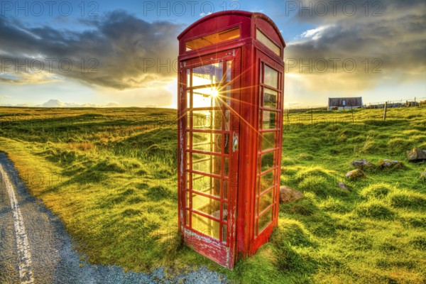 Urban red telephone box in the middle of a green countryside. Concept for synergy between modern