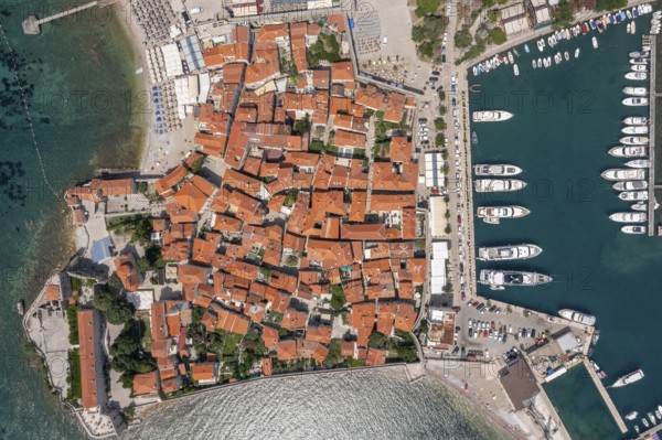 Aerial top view of walled old town of Budva city. Pier with moored yachts and boats. Adriatic sea,