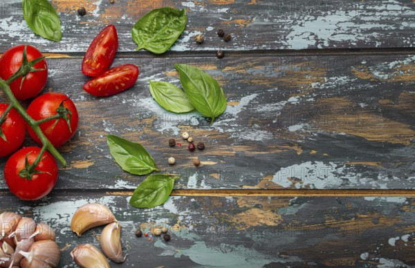 Food cooking border with cherry tomatoes, fresh green basil and garlic cloves top view on rustic