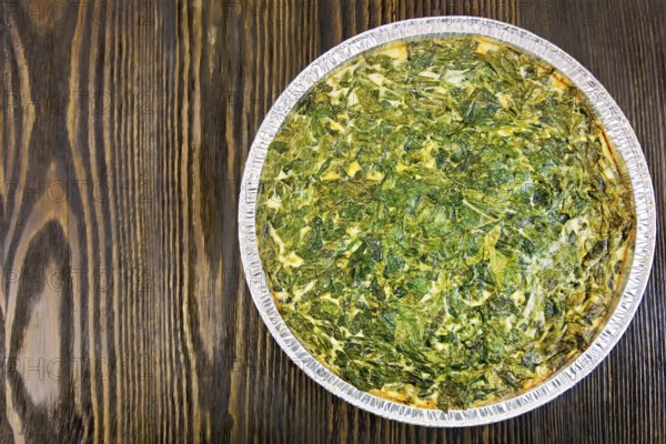 Celtic cake with spinach, tomatoes, oatmeal and eggs in baking dish from a foil against the