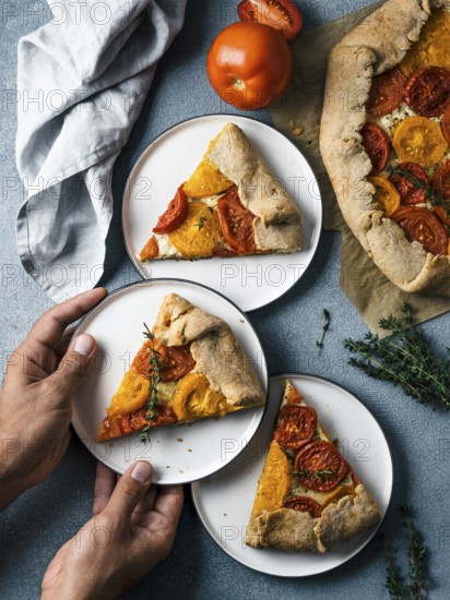 Savory fresh homemade tomato tart or galette.Hands takes piece of pie.Ideas and recipes healthy
