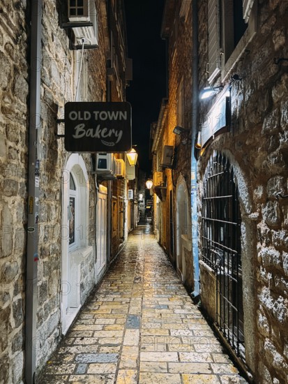 Budva, Montenegro - 25 december 2022: Signboard on a narrow street with stone houses. Caption: Old