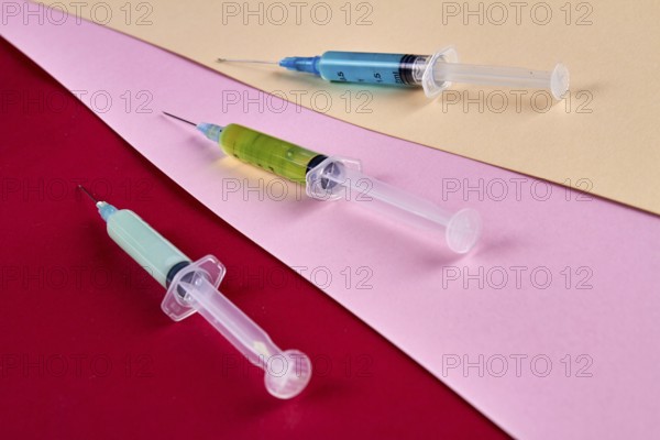 Close-up three syringes filled with multicolored medicine liquids. Drugs addiction and injections