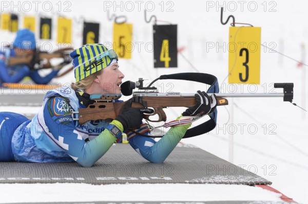 Sportswoman biathlete Legostaeva Anastasia rifle shooting in prone position. Biathlete in shooting