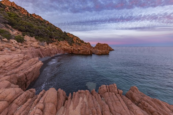 Large red rocks at the edge of the sea under a cloudy evening sky, Spiaggia di Cala E'Luas,