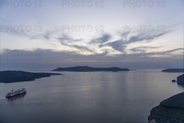 Evening atmosphere after sunset over the island of Thirassia, cruise ship in the archipelago of