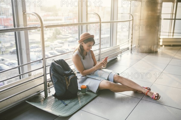 Theme of tourism and travel of young student. Beautiful young caucasian girl in dress and hat sits
