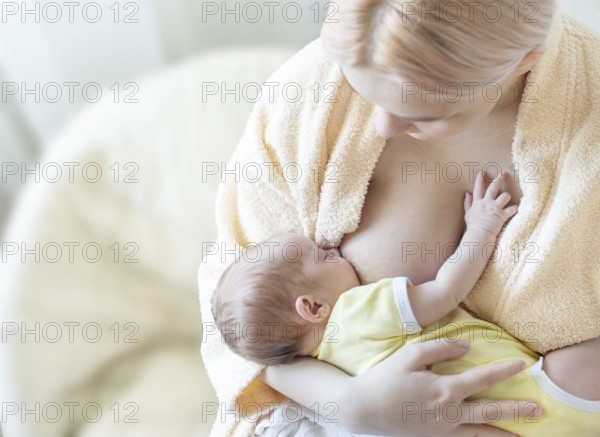 Baby eating breast milk. Caucasian blonde young mother breastfeeding her baby horizontal photo.