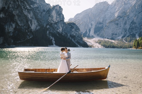 Bride and groom sailing in wooden boat, with oars at Lago di Braies lake in Italy. Wedding in