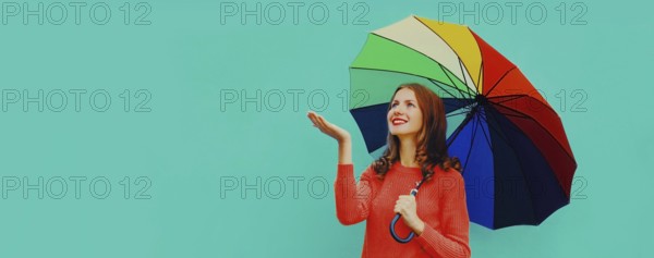 Autumn portrait of happy smiling young woman holding colorful umbrella wearing red knitted sweater
