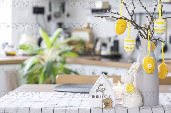 Key to house of cozy home with Easter decor with rabbit and eggs on table of kitchen. Building,