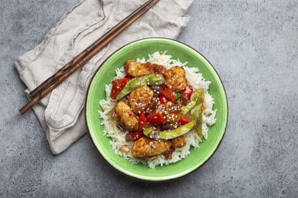 Asian sweet and sour sticky chicken with vegetables stir-fry and rice in ceramic bowl with