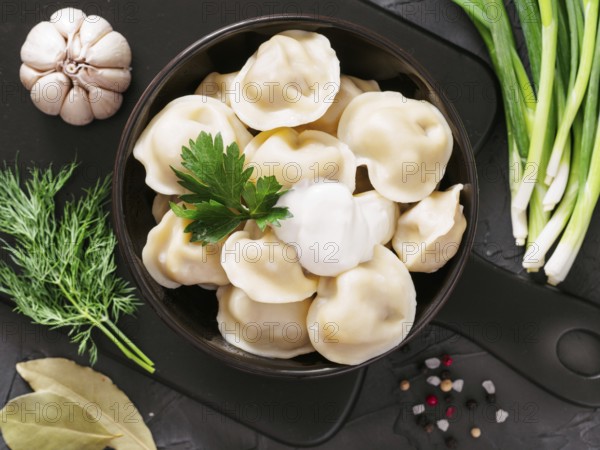 Traditional russian pelmeni, ravioli, dumplings with meat on black concrete background. Top view or