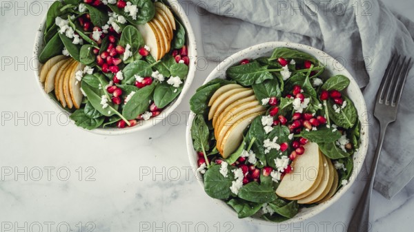 Fresh salad with baby spinach, pear, pomegranate and cottage cheese. Two bowls with delicious