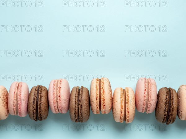 Macarons with copy space. Row of perfect french macarons or macaroons on blue background. Top view