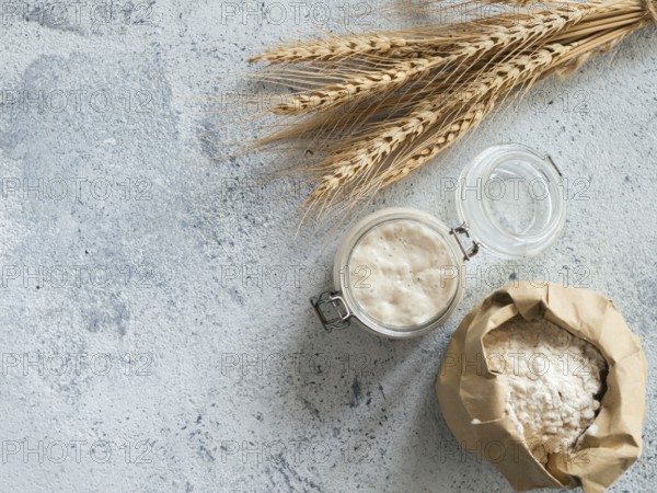 Wheat sourdough starter. Top view of bread making ingredients - glass jar with sourdough starter,