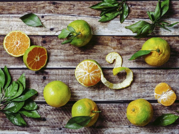 Green mandarines on old wooden background. Fresh ripe half, whole and peeled green tangerines with