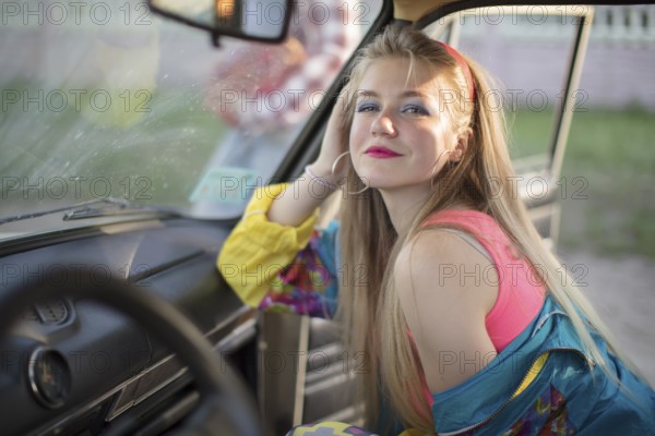 Beautiful girls in the style of the 90s in bright clothes in the salon of the car