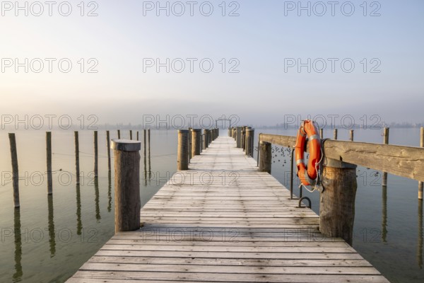 A jetty leads into a foggy lake, a lifebuoy hangs from a wooden railing, harbour, Allensbach,