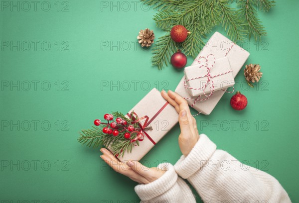 Christmas or New Year celebration green paper festive background with female hands holding wrapped