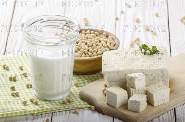 Non-dairy alternatives Soy milk or yogurt in mason jar and tofu on white wooden table with soybeans