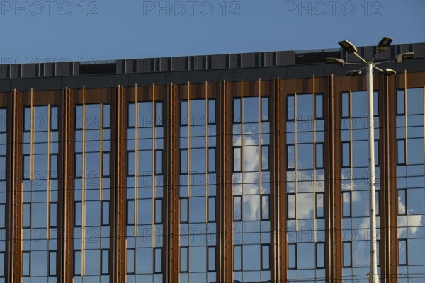 Modern office building exterior with glass facade on clear sky background. Transparent glass wall