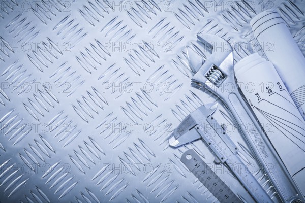 Engineering drawings vernier caliper monkey spanner on channeled metal background construction