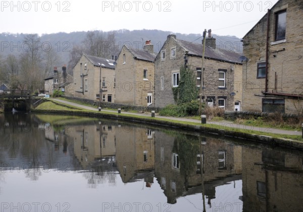 Houses alongside the rochdale canal in hebden bridge with reflections in the water and lock gates