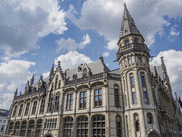 Large historic building with Gothic architecture and towers under a blue sky with clouds, Ghent,