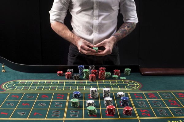 A close-up vibrant image of green casino table with roulette, with the hands of croupier and