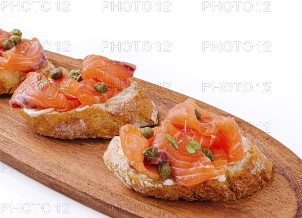 Food, Delicious canapés topped with smoked salmon and capers rest on a wooden platter. The vibrant