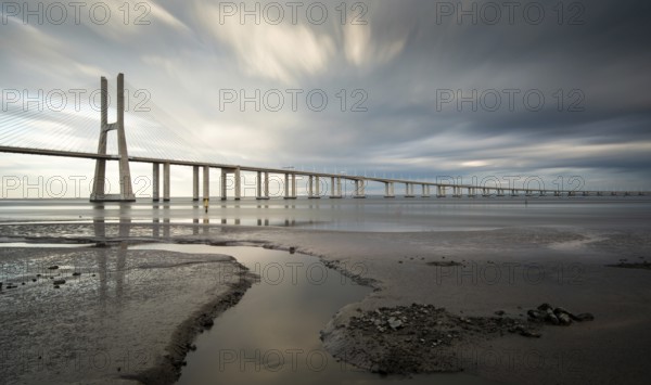 Vasco da Gama Bridge at sunset with dramatic cloudy sky in Lisbon Portugal. Long exposure