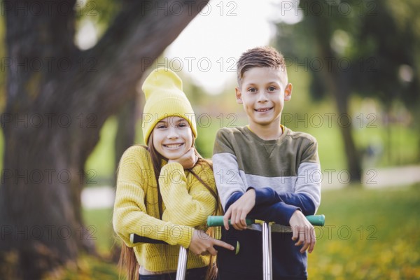 Caucasian children twins boy and girl schoolchildren age pose together in sunny weather in autumn