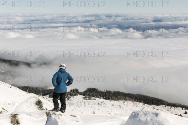 Freestyle skier is looking from the top of a peak of Vitosha mountain covored in clouds. He is