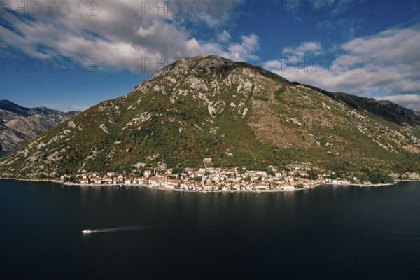 Boat sails along the Bay of Kotor against the backdrop of the coast of Perast at the foot of the