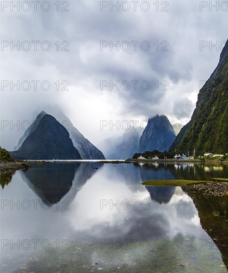 Magic country of fantastic heroes. New Zealand. Storm clouds cover the sky. Mirror-smooth water of